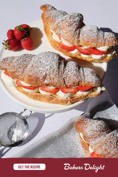 two pastries on a plate with strawberries and powdered sugar next to them