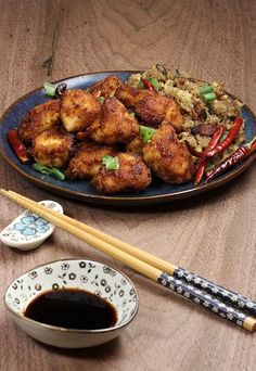 a plate full of food with chopsticks next to it on a wooden table