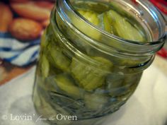 a jar filled with pickles sitting on top of a white cloth covered tablecloth