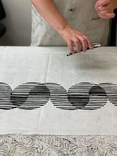 a person is using scissors to cut out designs on a piece of paper with black and white stripes