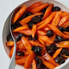 a bowl filled with carrots and raisins on top of a white table