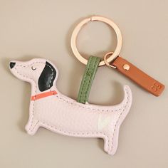 a keychain with a dog on it is hanging from a leather cord and has a metal hook in the shape of a dog