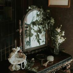 a mirror sitting on top of a wooden table next to a vase filled with flowers