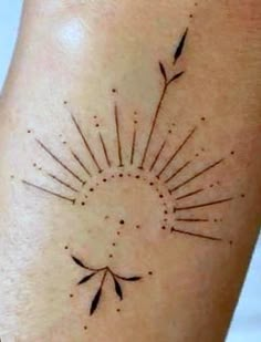 a sun tattoo on the back of a woman's leg, with arrows pointing towards it