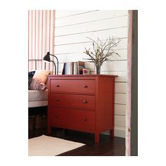 a red dresser sitting next to a bed in a bedroom