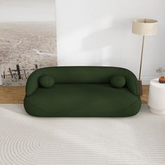 a green couch sitting on top of a white rug in a living room next to a lamp