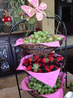 three baskets filled with grapes and strawberries on top of a table next to other fruit