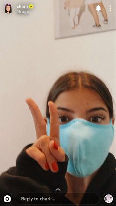 a woman wearing a face mask and making the peace sign with her hand in front of her