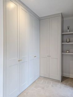 an empty room with white cupboards and shelves on the wall, along with carpeted flooring