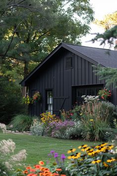 a black house surrounded by flowers and trees