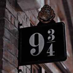 a black and white sign hanging from the side of a building next to a brick wall