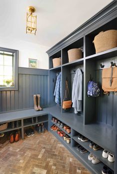 a blue mudroom with lots of shoes and bags on the shelves, in front of a window