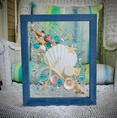 a blue frame with shells and seashells in it on a wicker chair