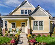 a yellow house with white trim on the front door and windows, along with landscaping