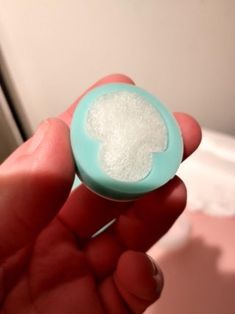 a hand holding a small powdered item in it's palm