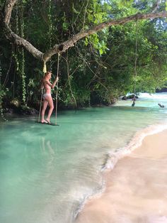 a woman standing on a rope in the middle of a body of water with trees around her