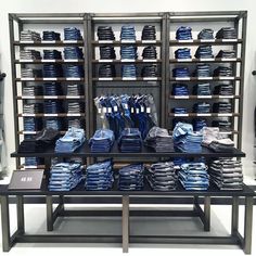 a display case filled with lots of blue and white shirts on metal shelves next to each other