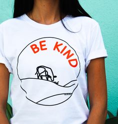 Because is there any other way to do it?! Super soft and comfy, our Be Kind tee is the perfect way to spread the vegan message in a subtle, powerful way.   This tee has: RIDIC COMFORT This 100% Combed Ring-Spun Cotton tee will not only let you show off your plant-based vibes in a chic way, but you'll also love the super soft feel and be comfy AF. MAD STYLE This tee features a crew neckline. It looks ridiculously super cool with pretty much anything you pair it with.  DOPE QUALITY All of our shir Vegan Clothing, Vegan Shirt, Vegan Gifts, Yoga Tank Tops, Crop Shirt, Be Kind, Womens Clothing Tops, Cotton Tee, Plant Based