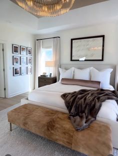 a large bed sitting in a bedroom under a chandelier and a painting on the wall