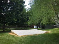 a concrete slab in the middle of a grassy area with trees and fence behind it