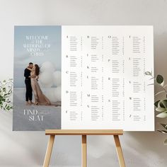 a wedding seating chart on a easel next to a potted plant and white wall