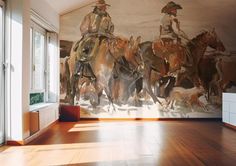 a large painting on the wall of a room with wooden floors and two men riding horses