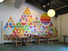 a room with colorful wallpaper and chairs in front of the walls is decorated with geometric shapes