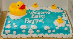 a blue cake decorated with rubber ducks and the words welcome baby paton on it