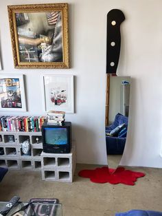 a living room with a tv, bookshelf and an art piece hanging on the wall