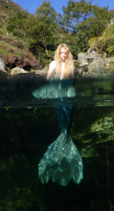 a woman is swimming in the water with her hair blowing back and looking at the camera