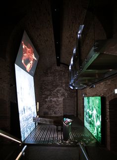 an empty room with two large screens on the wall and stairs leading up to it