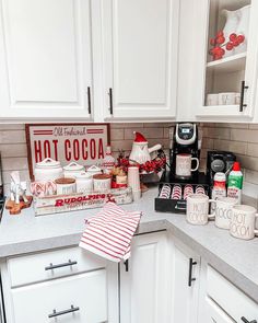 the kitchen counter is covered with coffee and hot cocoa items, including two mugs