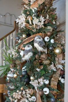 a decorated christmas tree with owls and pine cones on the top, surrounded by other ornaments