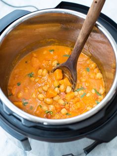 a wooden spoon in a slow cooker filled with chickpeas and carrots