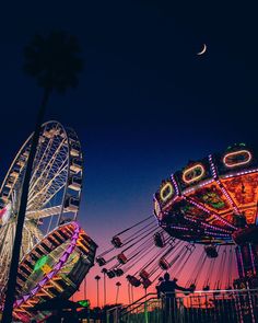 an amusement park at night with ferris wheel and carnival rides in the foreground as the sun sets