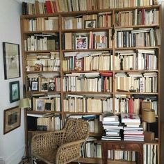 a bookshelf filled with lots of books next to a wicker chair