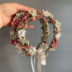 a hand holding a wreath with flowers on it