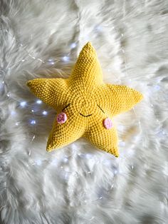 a yellow stuffed star laying on top of a white blanket