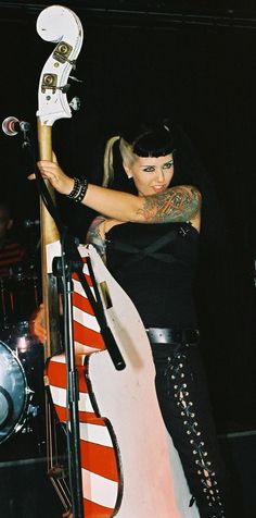 a woman standing next to a guitar on top of a stage