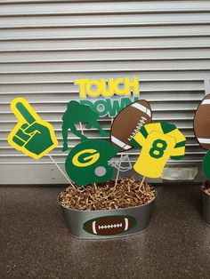 two tins filled with cupcake toppers and football cutouts sitting on a table