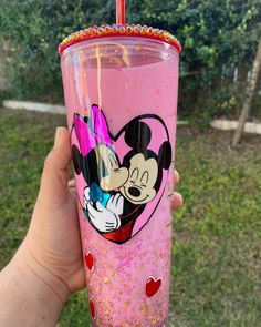 a person holding a pink cup with mickey mouse on it