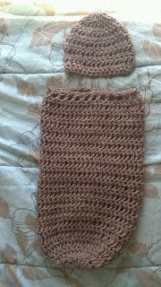 a crocheted brown bag sitting on top of a bed next to a pillow