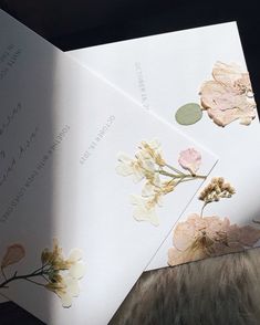 two wedding cards with pressed flowers on them, one is folded and the other is open