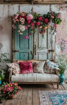 a couch sitting in front of a wooden door with flowers hanging from it's ceiling