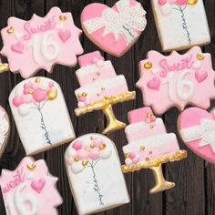 decorated cookies with pink and white frosting are arranged on a wooden table, next to each other