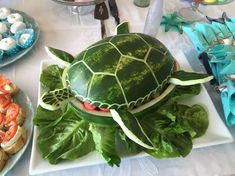 a watermelon turtle is sitting on top of lettuce and tomato slices