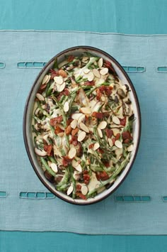 a bowl filled with green beans and almonds on top of a blue place mat