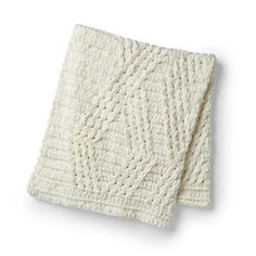 a white knitted blanket on top of a table