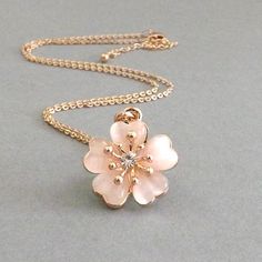 Rose Gold Cherry Blossom Necklace made from Cats Eye - Pink Spring Necklace A delicate pink cherry blossom in 10K rose gold plating and pale pink cat's eye beads with a center rhinestone make this a beautiful addition to your wardrobe. Makes a wonderful: Gift for Mom Bridesmaid Gift Flower Girl Gift Bride's Necklace for Cherry Blossom Theme Anniversary Gift The cherry blossom bloom is approximately 7/8 inch. The pale pink cat's eye beads are surrounded by rose gold plating. The rose gold plated Dainty Blossom-colored Wedding Jewelry, Dainty Blossom Wedding Jewelry, Delicate Rose Gold Flower Necklaces, Feminine Flower Pendant Necklace For Wedding, Feminine Blossom-colored Wedding Jewelry, Pink Flower Charm Necklace For Wedding, Delicate Peach Jewelry For Gifts, Pink Flower Shaped Necklace For Weddings, Feminine Rose Gold Flower Pendant Necklace