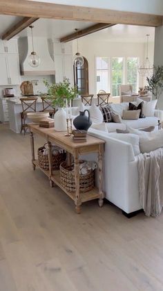 a living room filled with white furniture and lots of wood flooring on top of it